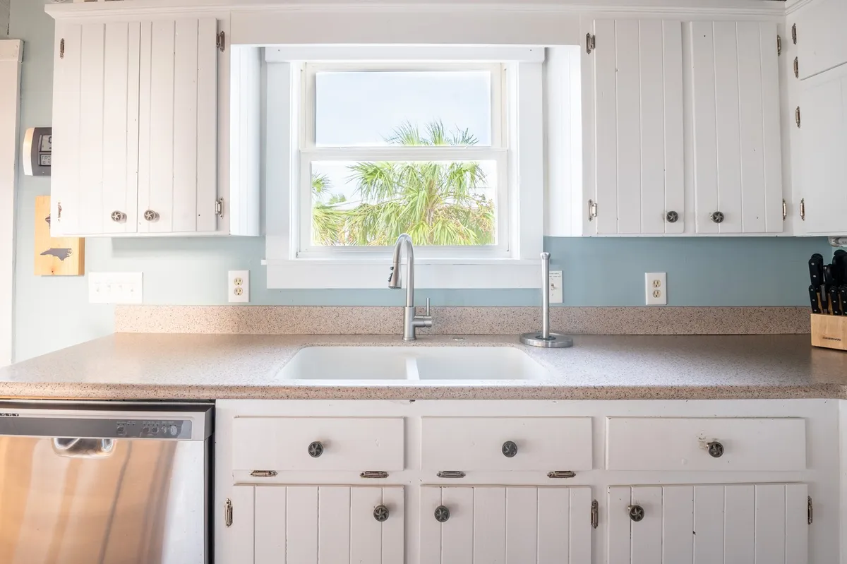 A bright, functional kitchen is shown with a window over the sink, ample countertop space, and modern appliances. The kitchen is ready for meal prep and group cooking sessions, with light streaming in to create a welcoming atmosphere.